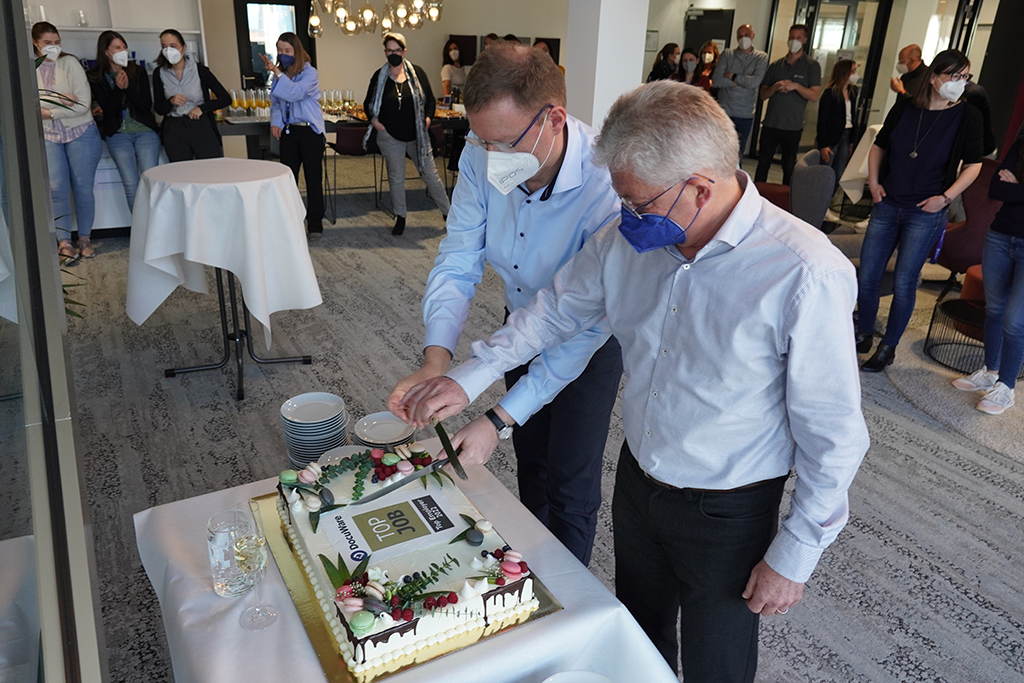 Die Docuware-Geschäftsführer Max Ertl und Dr. Michael Berger feiern die Auszeichnung mit Torte und Belegschaft (Bild: Docuware)